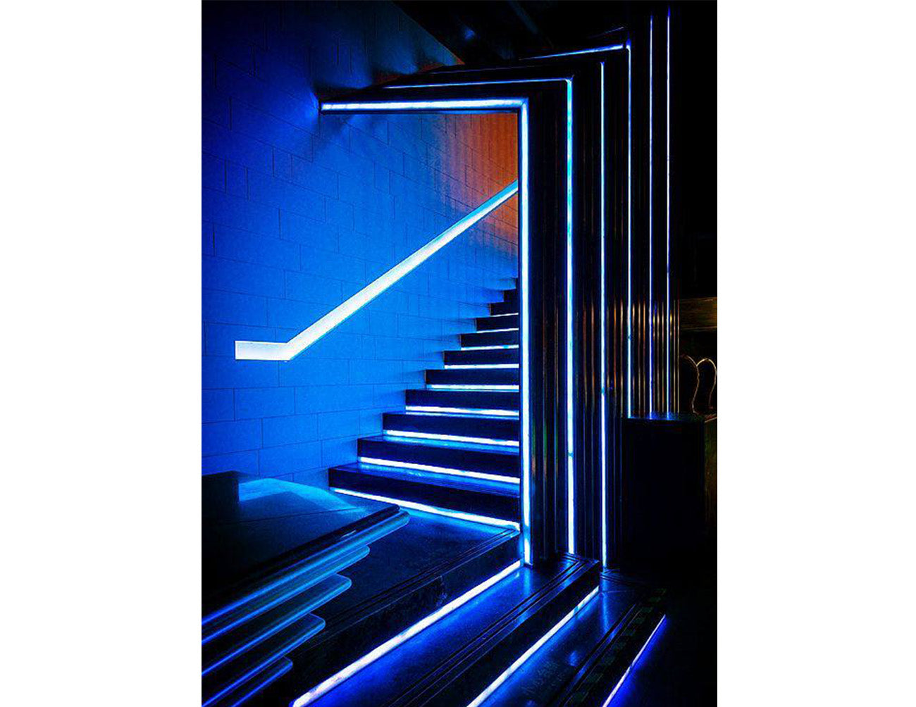 A staircase is decorated with blue LED strip lights that are powered by a dimmable low voltage driver.