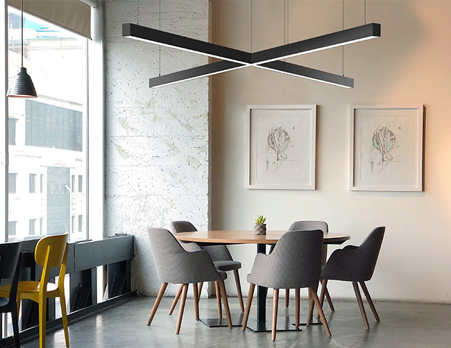 Black color cross-shaped LED linear light fixtures are suspended and illuminating a dining area.