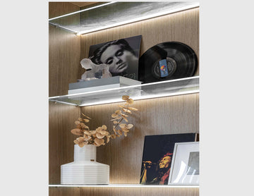 LED strip lights are used in an aluminum channel to create a unique lighting design for a shelving unit.