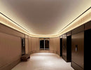 LED strip lights are used in an aluminum channel to illuminate a hallway with elevators.