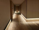 LED strip lights are used in an aluminum channel to illuminate a hallway with wall washing lights.