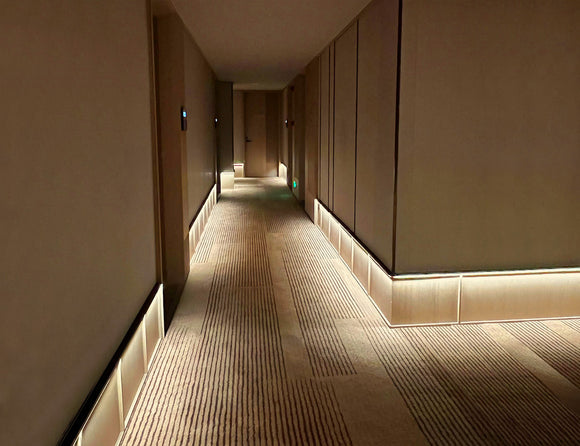 LED strip lights are used in an aluminum channel to illuminate a hallway with wall washing lights.