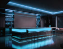 A sleek bar counter with RGBW lighting effects beneath and behind the shelves. The lighting is controlled by an RGBW Remote Controller, creating a colorful and dynamic atmosphere.