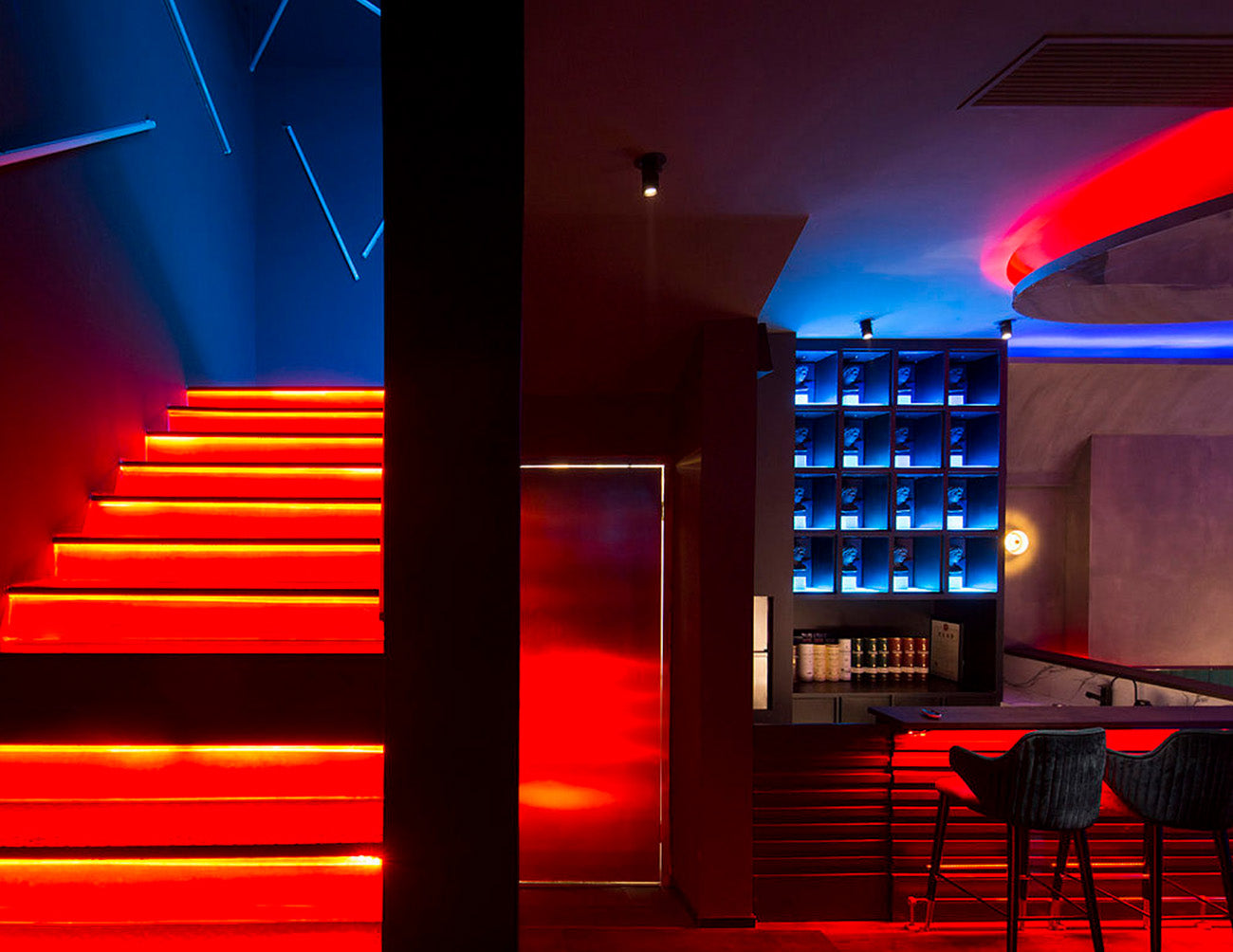 A restaurant staircase is decorated with RGB LED strip lights that are powered by a dimmable low voltage transformer.