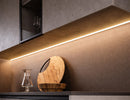 Corner surface mount aluminum undercabinet LED strip light integrated into kitchen cabinetry, delivering warm linear architectural lighting for countertop and wall applications.