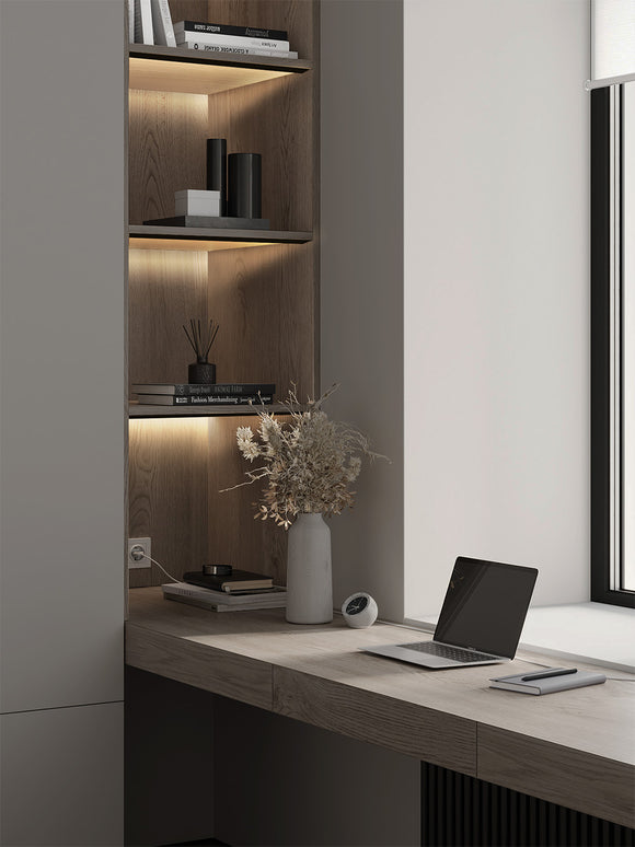 LED strip light installed in aluminum channel for shelf and under cabinet lighting, providing soft architectural illumination in a modern home office interior.