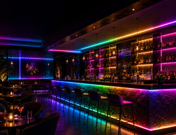 RGB SPI LED Strip - Digital Color-Chasing LED Tape Light integrated into a luxury bar with multicolor counter, bottle display and ceiling accent lighting.