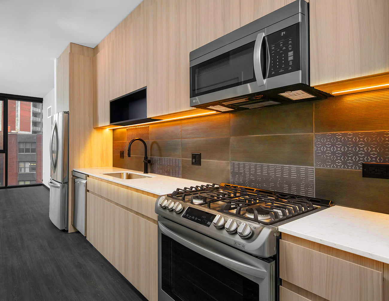 Undercabinet lights illuminate counter backsplashes in a kitchen space.