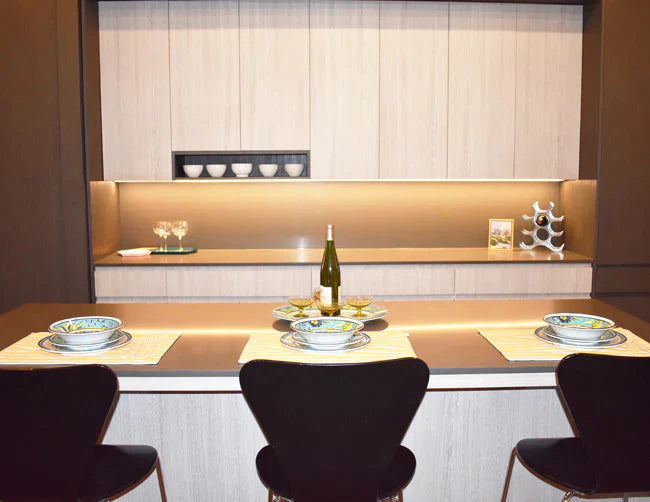 Undercabinet lights illuminate counter backsplashes in a kitchen space.