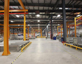 Many suspended LED Linear High Bay Lights illuminate a warehouse.