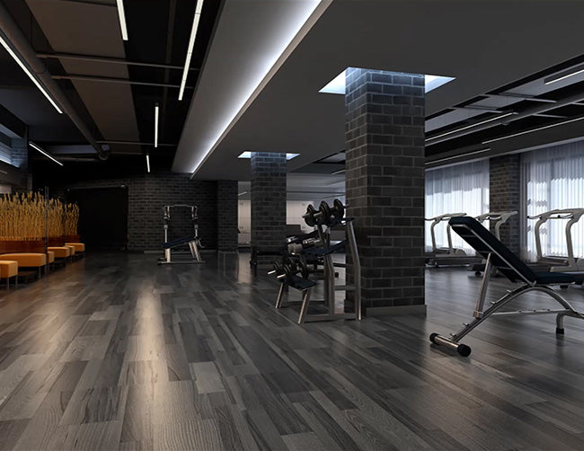 Black color GL LED L8050 8ft linear light fixtures suspended from ceiling illuminate a gym studio.