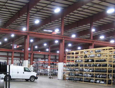 Many LED UFO High Bay Lights are suspended to illuminate a large warehouse.