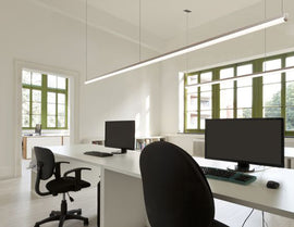 Suspended white color GL LED linear strip light fixture 8ft form long fixtures illuminating a computer lab.